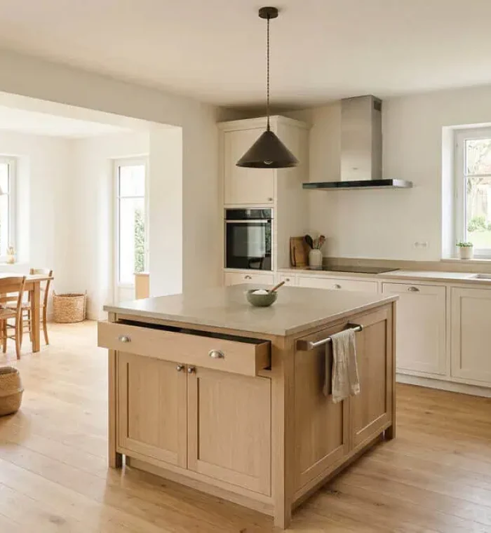 Îlot central en bois clair avec passages dégagés dans une cuisine moderne et lumineuse