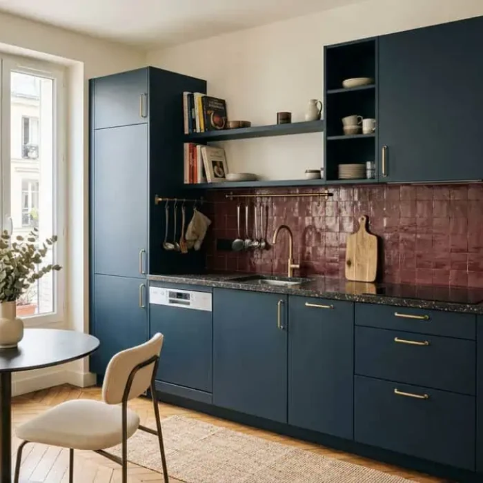 Cuisine équipée contemporaine bleu nuit avec plan de travail en terrazzo sombre, zellige bordeaux et laiton brossé