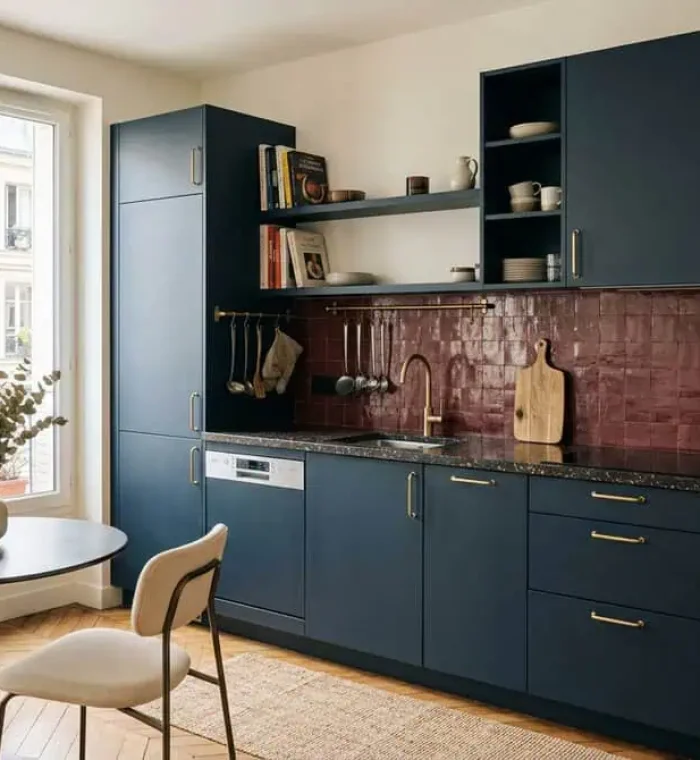 Cuisine équipée contemporaine bleu nuit avec plan de travail en terrazzo sombre, zellige bordeaux et laiton brossé